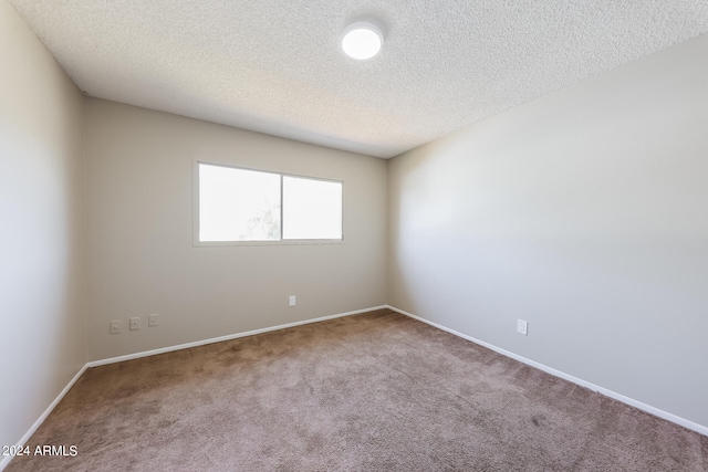 carpeted empty room featuring a textured ceiling