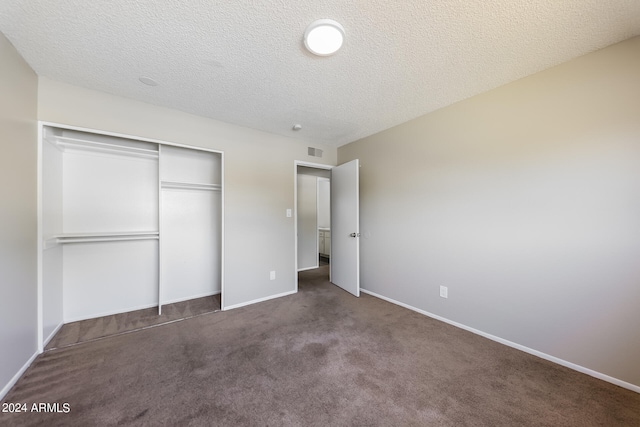 unfurnished bedroom with a textured ceiling, dark carpet, and a closet