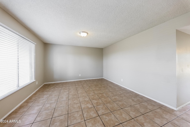 unfurnished room featuring a textured ceiling and light tile patterned floors