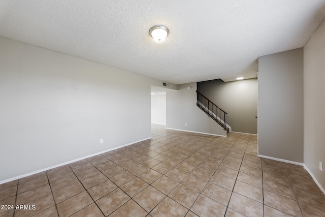 empty room featuring a textured ceiling and light tile patterned flooring