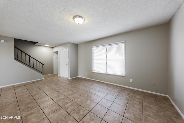 spare room with a textured ceiling and light tile patterned flooring