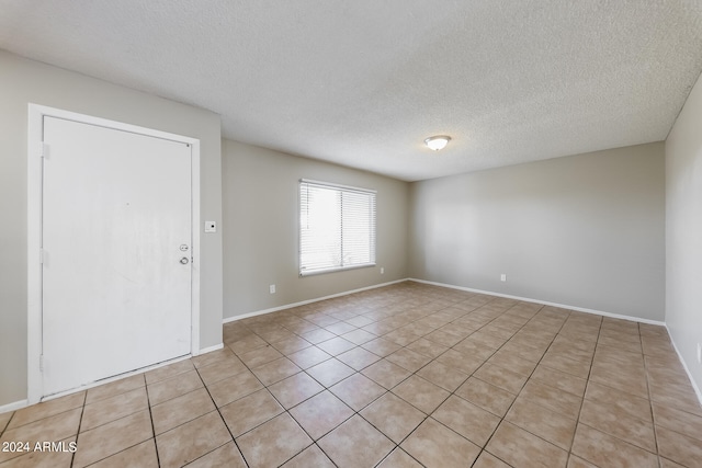 tiled empty room with a textured ceiling