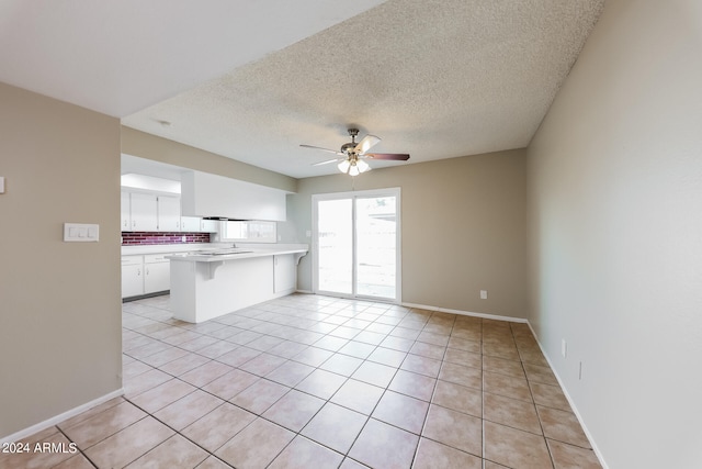 interior space with white cabinets, kitchen peninsula, ceiling fan, tasteful backsplash, and a textured ceiling