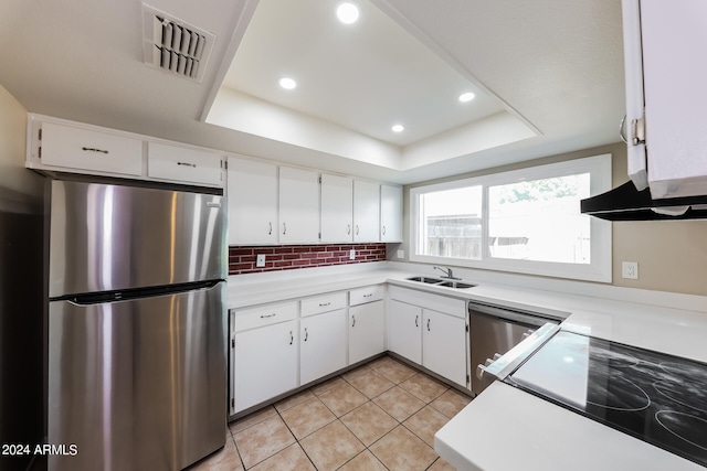 kitchen featuring a raised ceiling, sink, appliances with stainless steel finishes, and white cabinetry