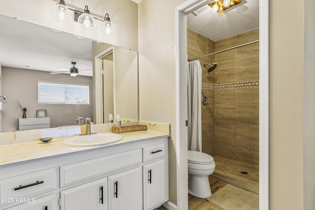 bathroom featuring curtained shower, hardwood / wood-style floors, vanity, toilet, and ceiling fan