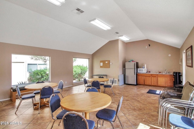 tiled dining space with vaulted ceiling and sink