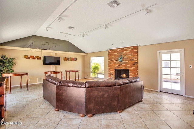 tiled living room with a brick fireplace, plenty of natural light, lofted ceiling, and track lighting