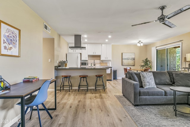 living room featuring ceiling fan and light hardwood / wood-style flooring