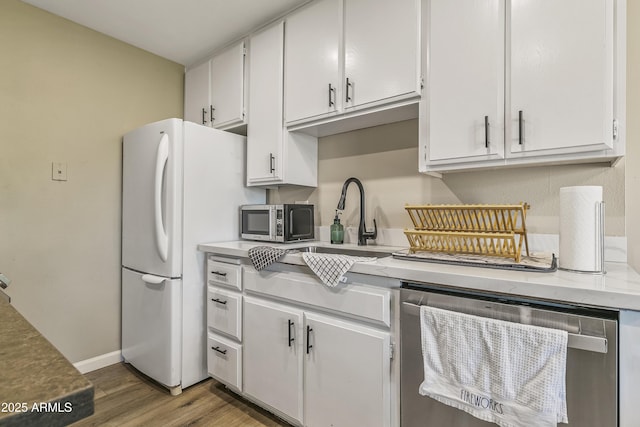 kitchen with appliances with stainless steel finishes, white cabinetry, dark hardwood / wood-style flooring, and sink