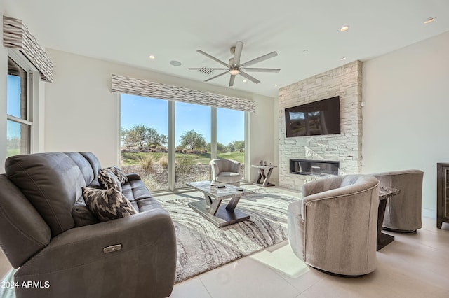 living room featuring ceiling fan and a stone fireplace