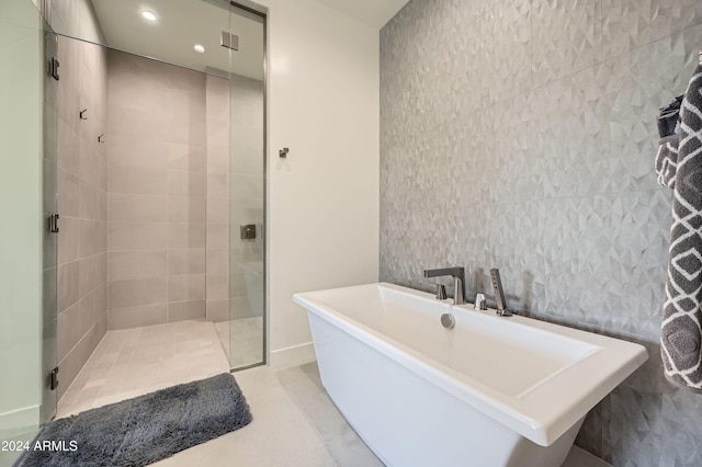 bathroom with tile patterned flooring, tile walls, and plus walk in shower