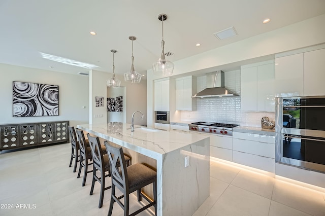 kitchen featuring white cabinetry, wall chimney range hood, sink, and appliances with stainless steel finishes