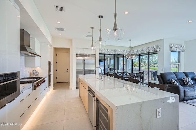 kitchen featuring pendant lighting, wall chimney range hood, wine cooler, a large island, and stainless steel appliances