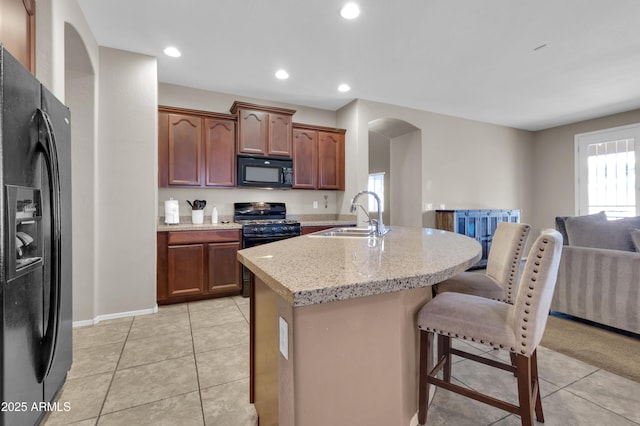 742 E Kingbird Dr, Gilbert, AZ 85297 - kitchen with black appliances, light tile patterned flooring, arched walkways, a breakfast bar area, and a center island with sink