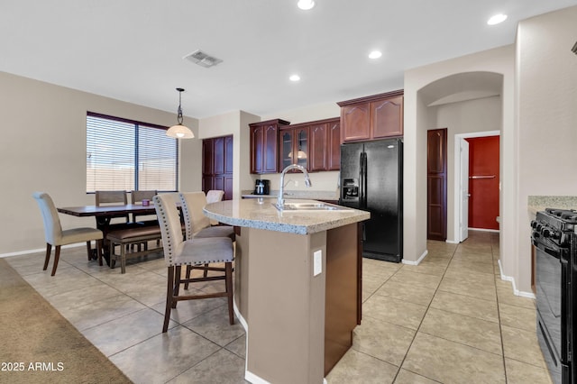 742 E Kingbird Dr, Gilbert, AZ 85297 - kitchen featuring black appliances, glass insert cabinets, light tile patterned floors, decorative light fixtures, and a breakfast bar