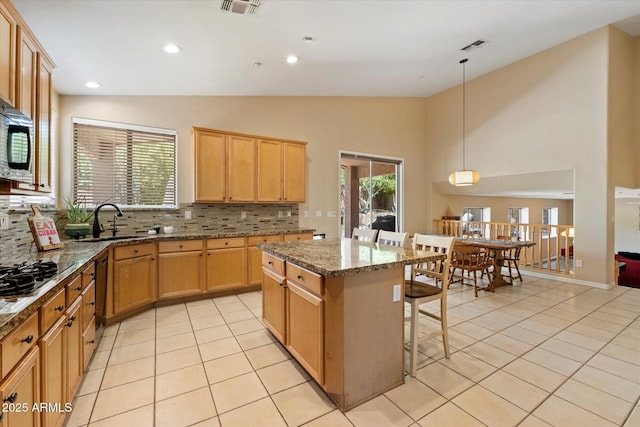 kitchen featuring a sink, light tile patterned floors, tasteful backsplash, and a kitchen breakfast bar