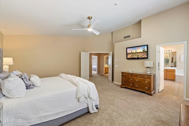 bedroom with visible vents, ceiling fan, a high ceiling, light colored carpet, and connected bathroom