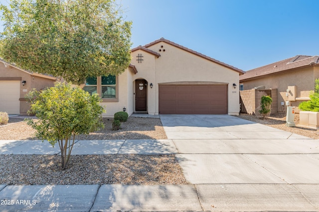 mediterranean / spanish house featuring fence, a tile roof, concrete driveway, stucco siding, and a garage