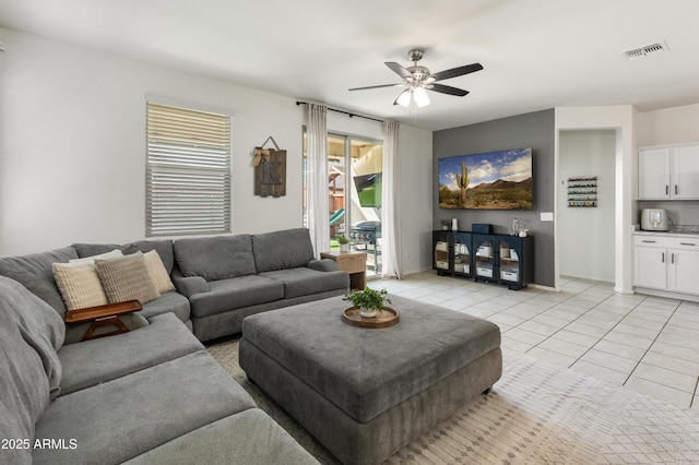 living area featuring light tile patterned floors, baseboards, visible vents, and ceiling fan