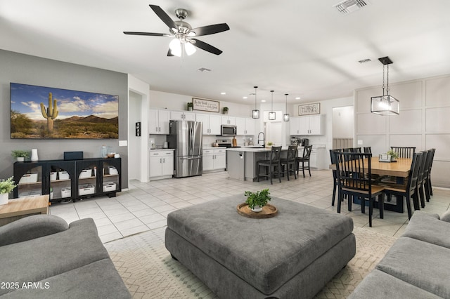 living room with light tile patterned floors, visible vents, and ceiling fan