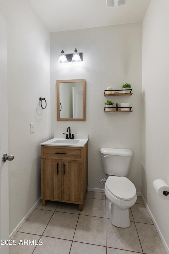 half bath with tile patterned flooring, toilet, vanity, and baseboards