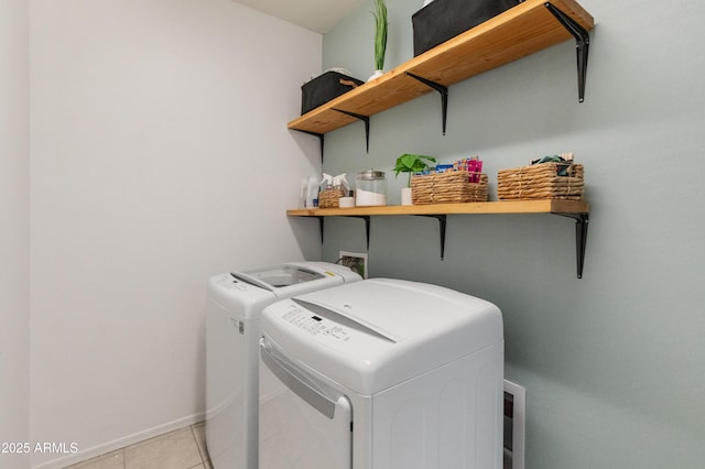 clothes washing area with light tile patterned floors, baseboards, independent washer and dryer, and laundry area