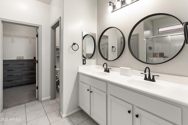 full bathroom featuring tile patterned floors, double vanity, a stall shower, and a sink