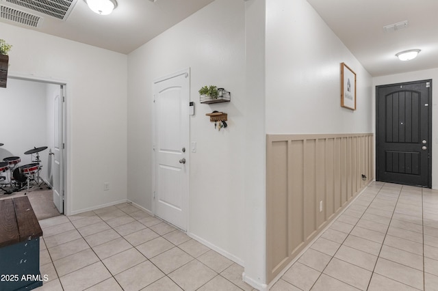 entrance foyer featuring light tile patterned flooring, visible vents, and a wainscoted wall