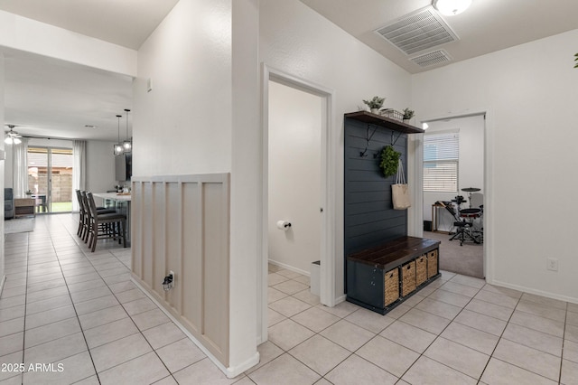 hall with light tile patterned floors, baseboards, and visible vents