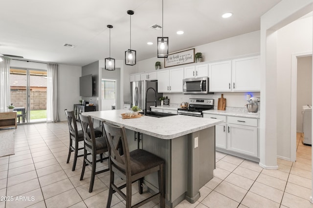 kitchen featuring visible vents, a center island with sink, light countertops, appliances with stainless steel finishes, and a sink