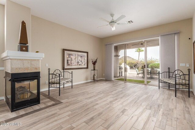 12841 N 19th St, Phoenix, AZ 85022 - living area with a tiled fireplace, a ceiling fan, baseboards, visible vents, and light wood-style floors