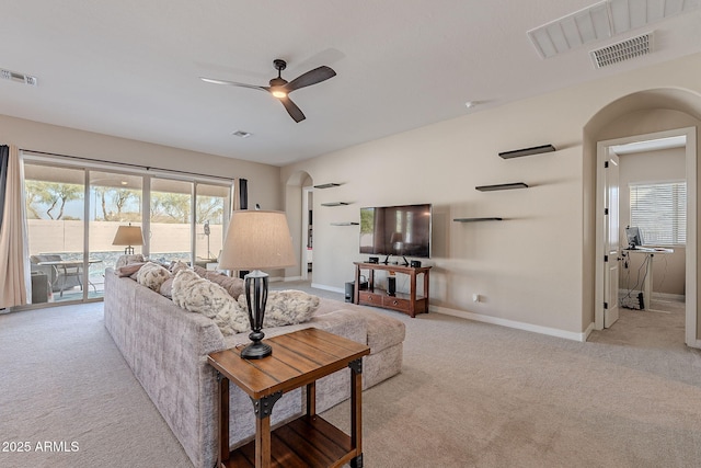 living room with light carpet, visible vents, arched walkways, and ceiling fan