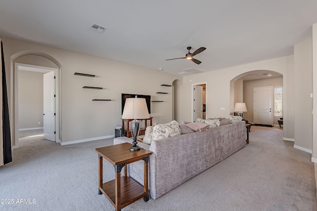 living area featuring visible vents, arched walkways, baseboards, and light colored carpet