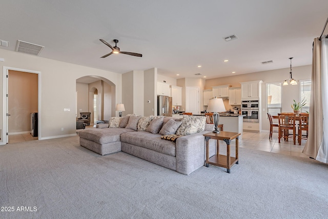 living room featuring light colored carpet, visible vents, arched walkways, and light tile patterned flooring