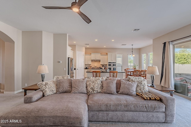 living room with light carpet, baseboards, arched walkways, a ceiling fan, and recessed lighting