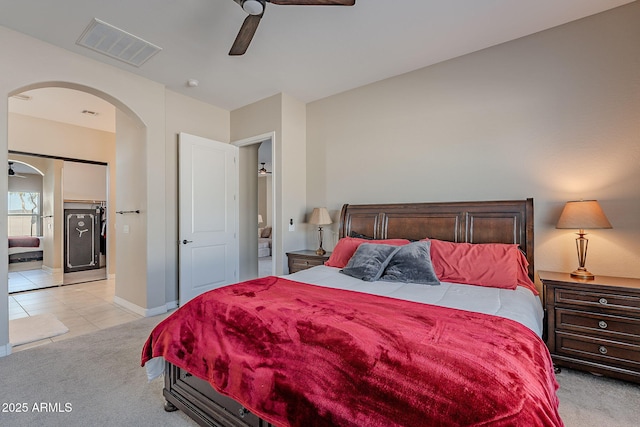 bedroom with arched walkways, light tile patterned floors, visible vents, light carpet, and ceiling fan