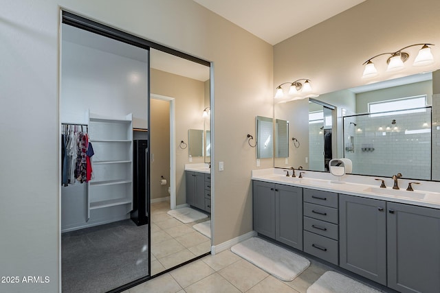 full bath featuring a tile shower, double vanity, tile patterned flooring, and a sink