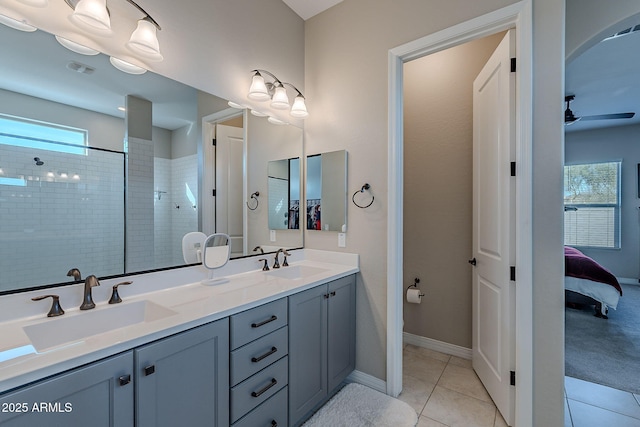 full bath with a tile shower, tile patterned flooring, a sink, and a ceiling fan