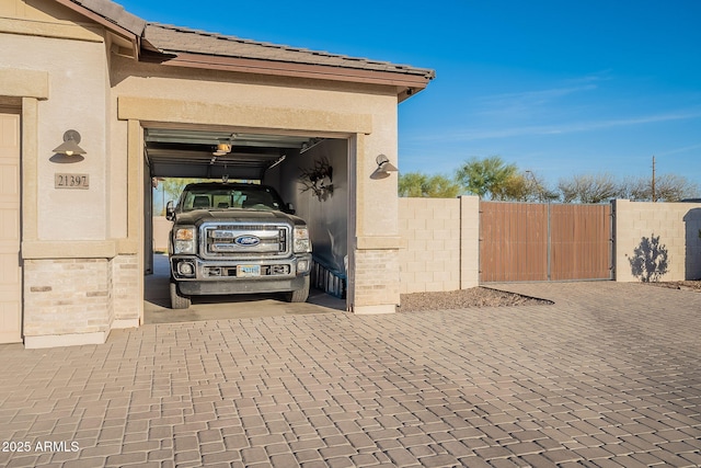 garage featuring a gate, driveway, and fence