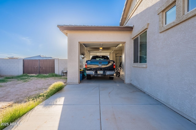 view of parking / parking lot featuring a garage, concrete driveway, and fence