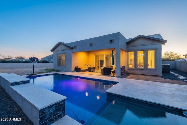 pool at dusk with a patio area, fence, and a fenced in pool