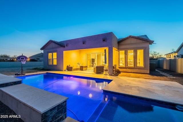 pool at dusk with a patio, a fenced backyard, and a fenced in pool