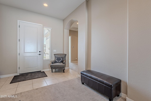 entrance foyer with arched walkways, carpet flooring, visible vents, baseboards, and tile patterned floors