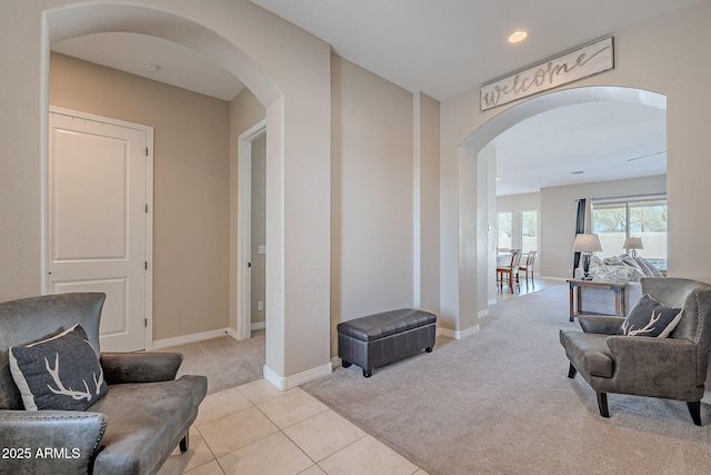 sitting room with light tile patterned floors, arched walkways, recessed lighting, light carpet, and baseboards