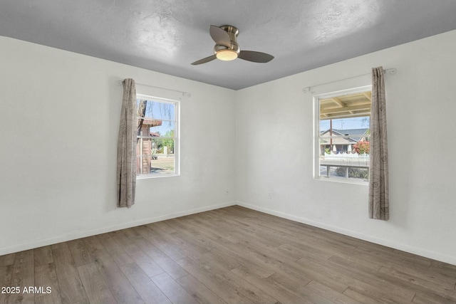 empty room featuring baseboards, wood finished floors, and a healthy amount of sunlight