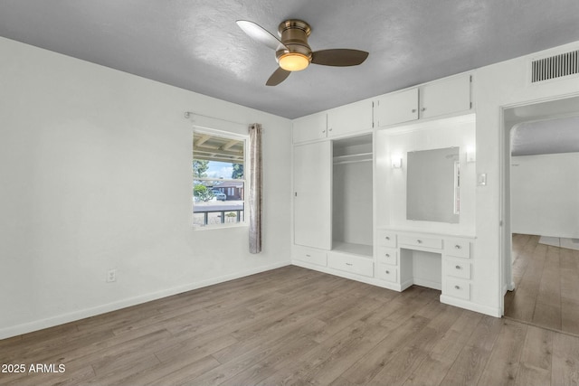 unfurnished bedroom featuring wood finished floors, a closet, baseboards, and visible vents