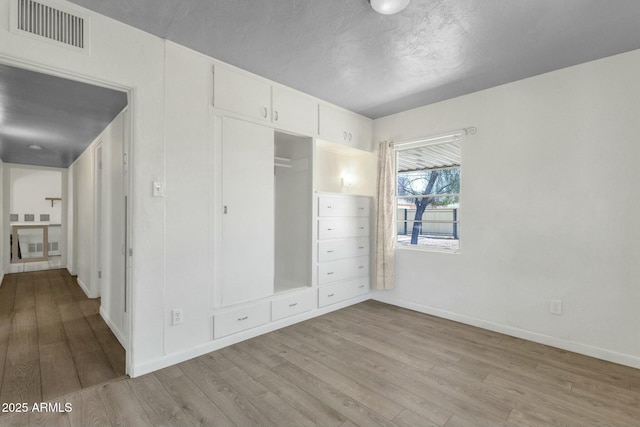 unfurnished bedroom with baseboards, visible vents, a closet, and wood finished floors