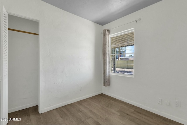 unfurnished bedroom featuring a closet, baseboards, and wood finished floors