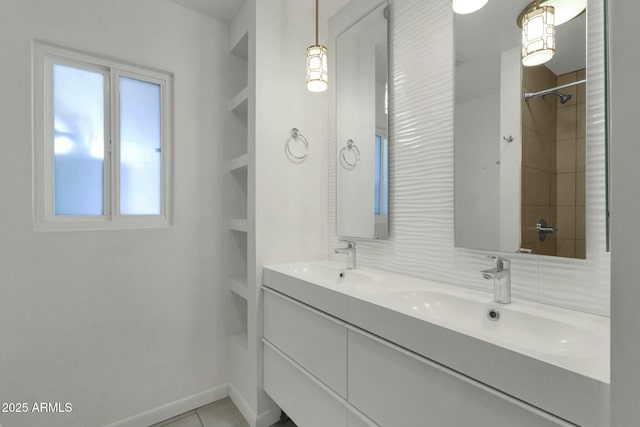 bathroom with baseboards, double vanity, a sink, and tile patterned flooring