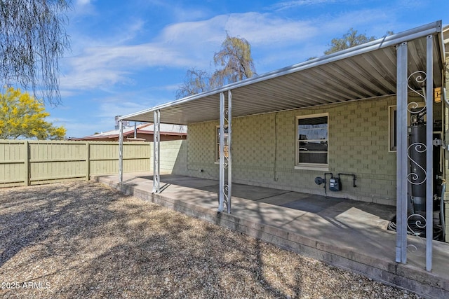 back of house featuring concrete block siding, fence, and a patio